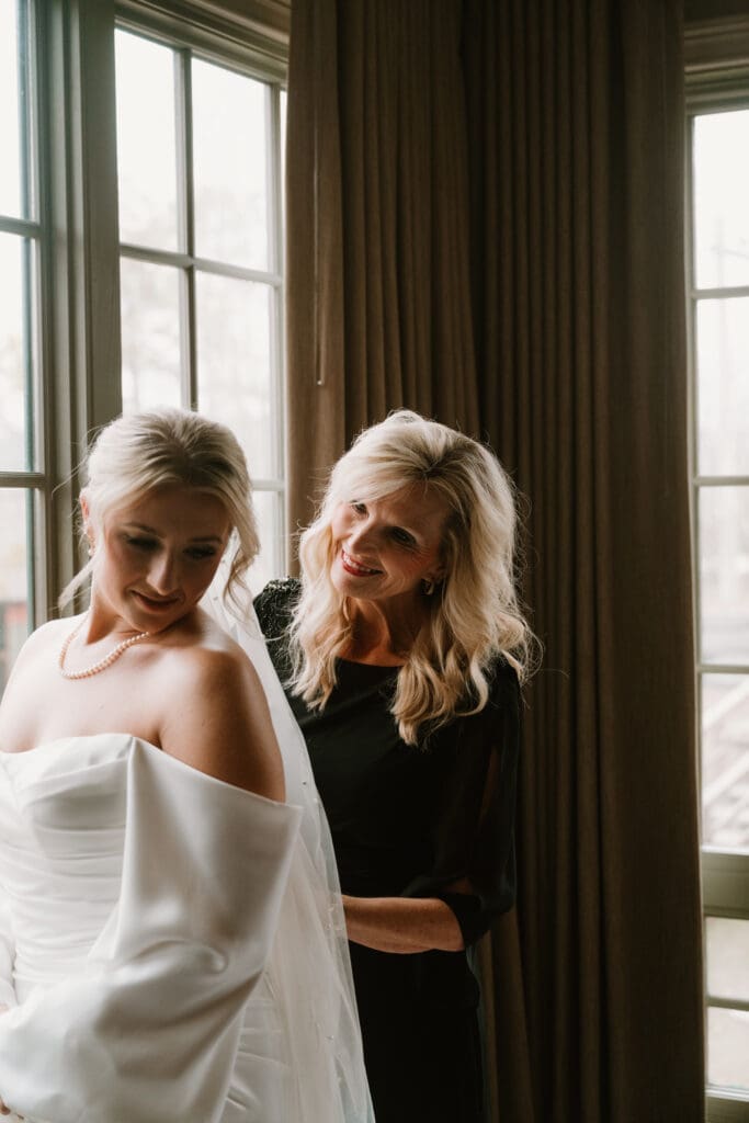 mother of the bride helping zip up her wedding dress