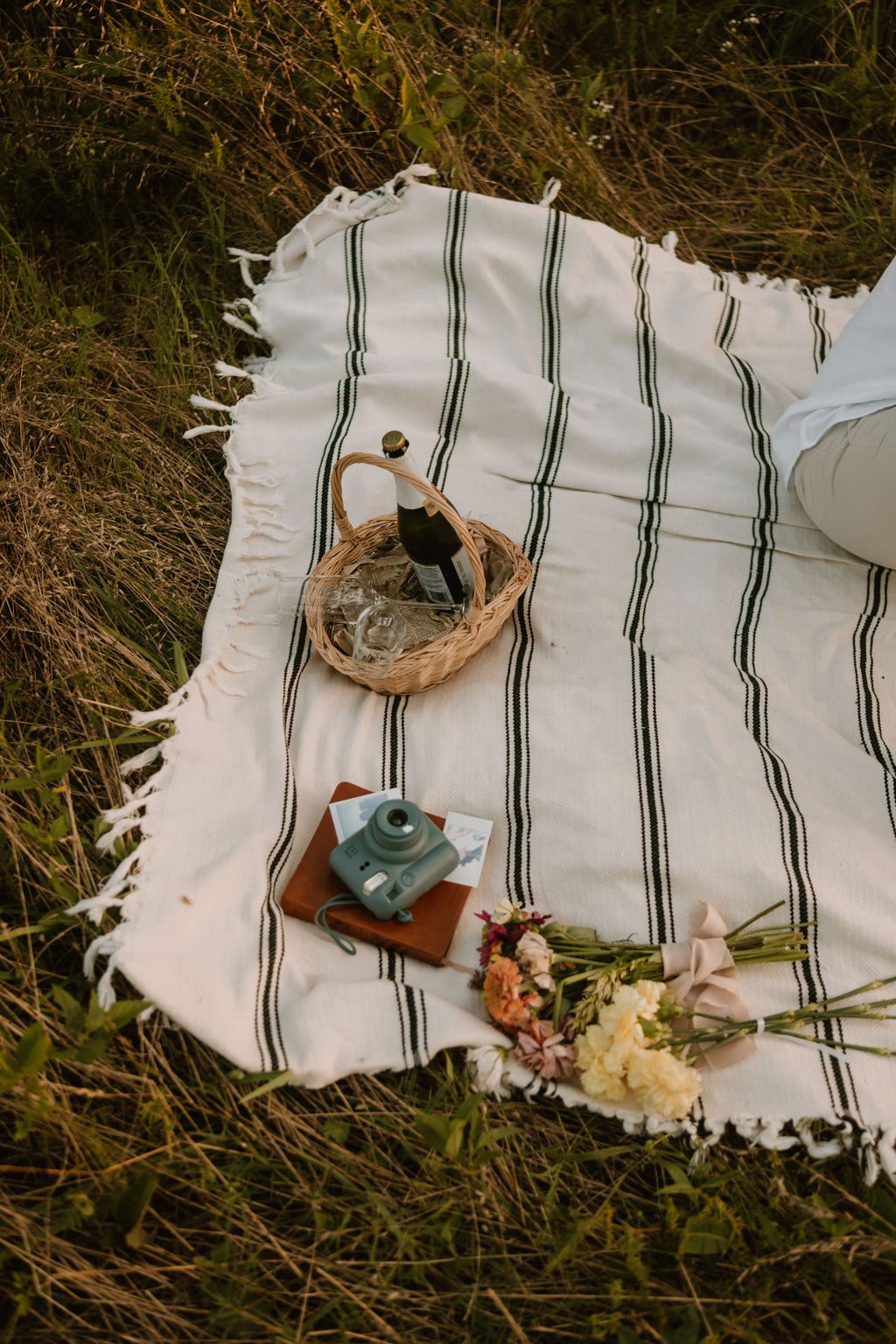 picnic blanket with champagne and flowers