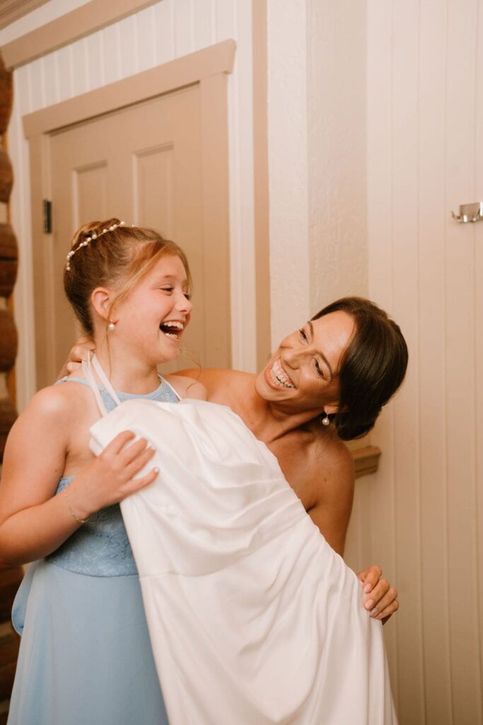 bride laughing with young daughter in dress
